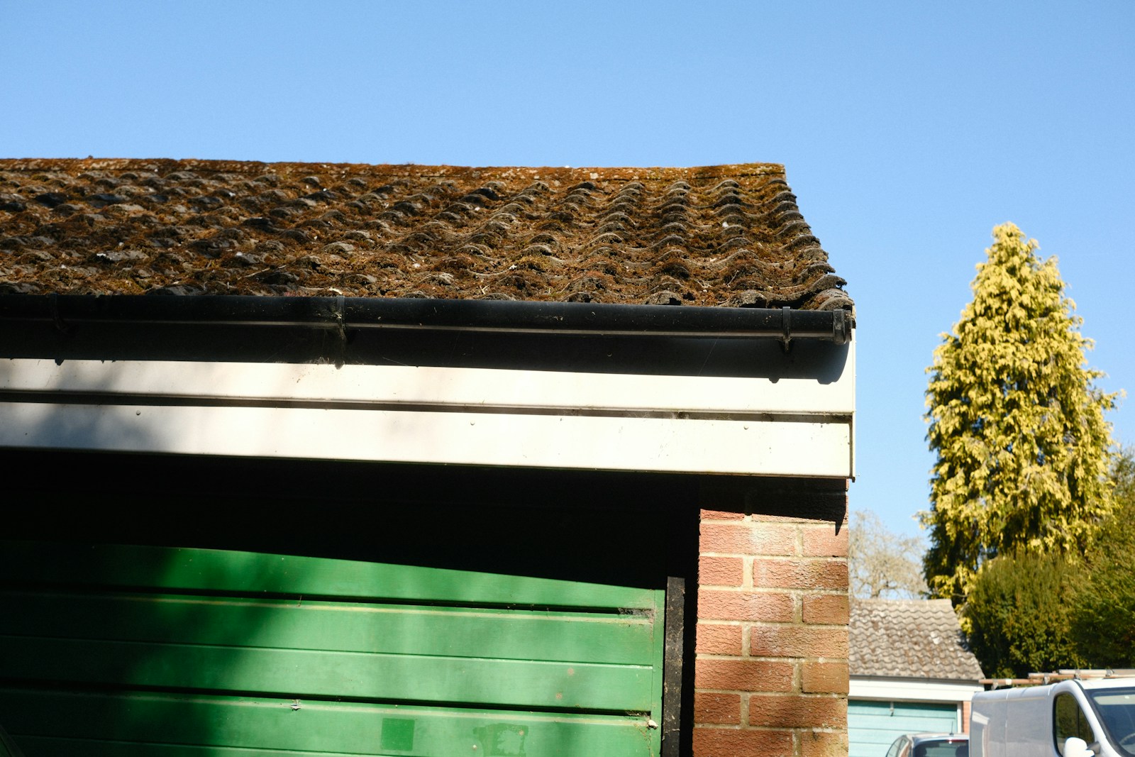 Green garage door next to brick wall and roof.