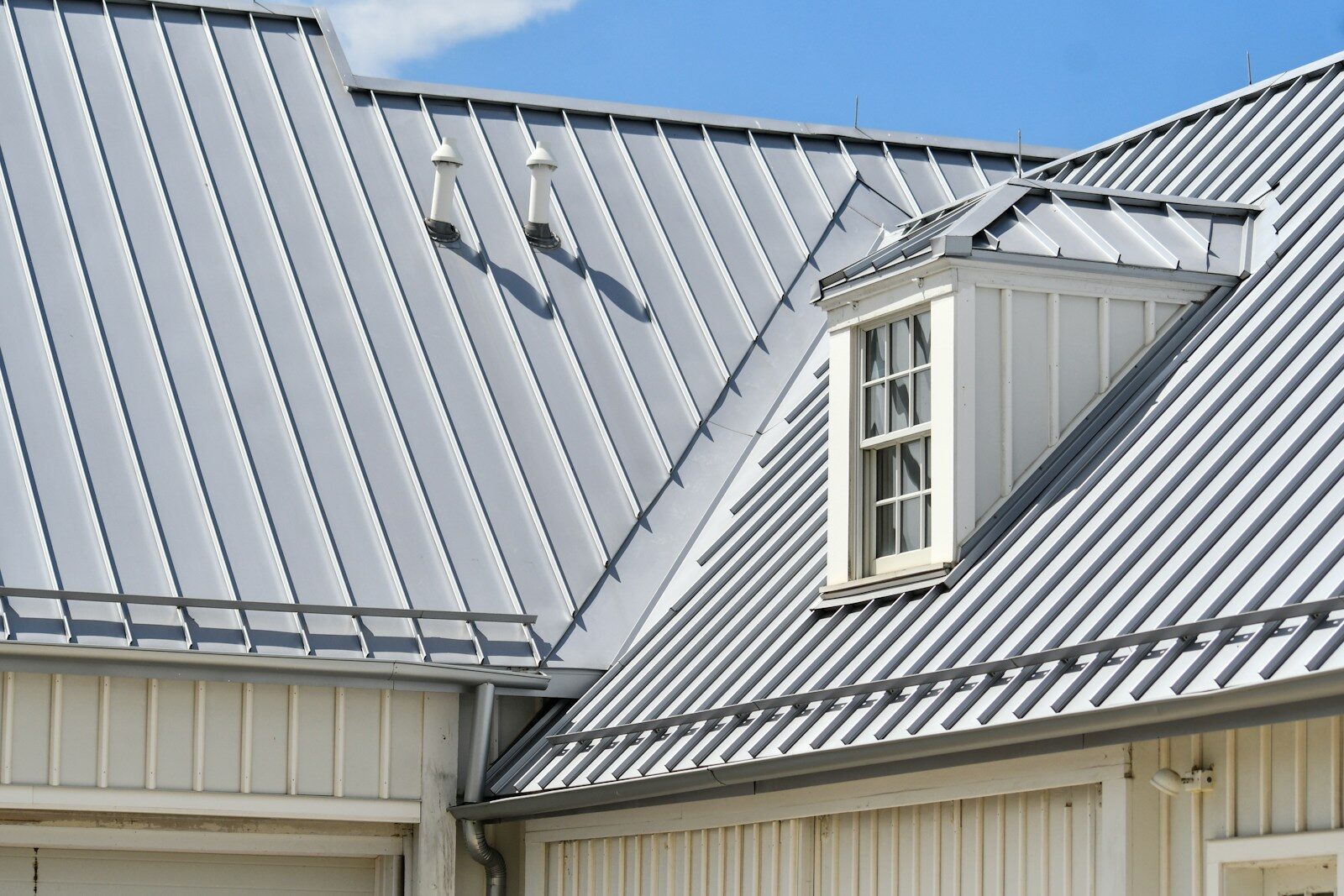 Grey metal roof, white siding, and a dormer window.