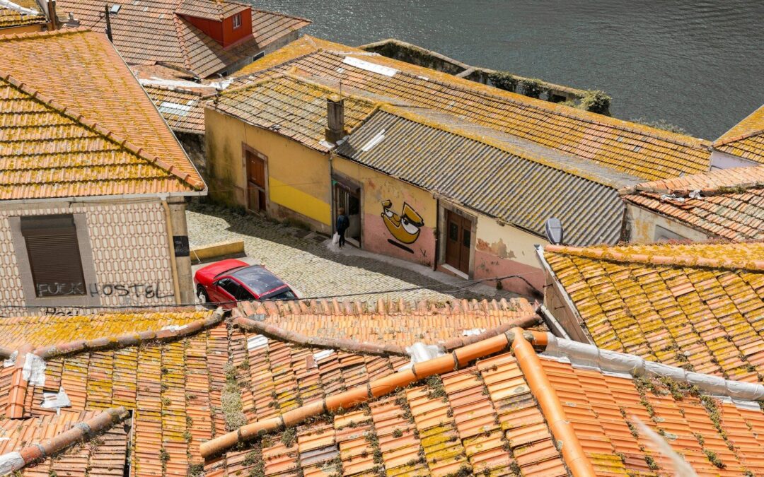 a red car parked on top of a roof next to a body of water