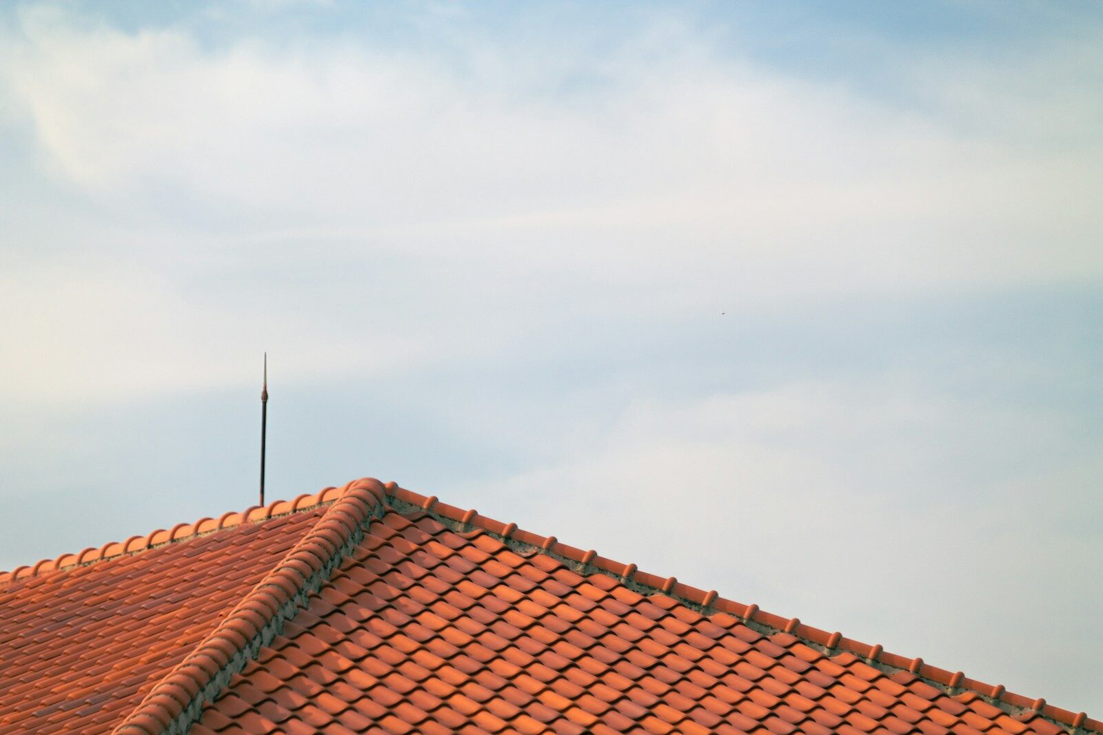 A red tiled roof with a blue sky in the background
